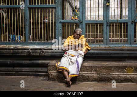 Kumbakonam, Tamil Nadu, Inde - février 2020 : un prêtre indien âgé assis sur une plate-forme en pierre de l'ancien temple hindou de Swamimalai. Banque D'Images