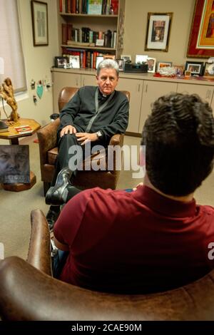 Dans son bureau d'une église catholique du sud de la Californie, un monseigneur d'âge moyen conseille un jeune paroishioner adulte. Banque D'Images