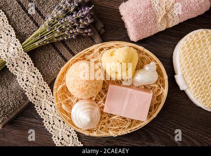 Vue de dessus encore la vie de divers produits de bain dans panier en osier de bois. Bombe de bain, barre de savon, éponge de mer naturelle avec coquillages de poire mère. Pose à plat. Banque D'Images