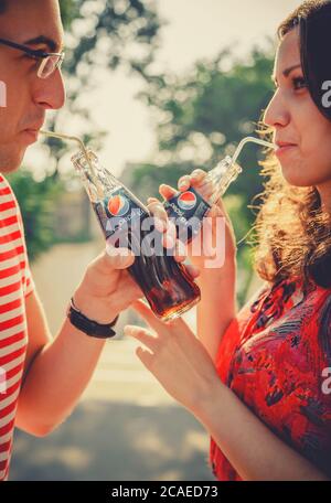 ODESSA, UKRAINE - 15 OCTOBRE 2014 : gros plan de jeunes couples heureux à l'extérieur de boire froid Pepsi à partir de bouteilles de verre avec de la paille et regardant chacun Banque D'Images