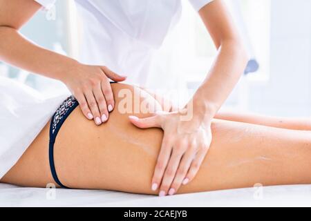 Massage des jambes et des fesses pour réduire la cellulite et préserver un look sain. Mains de womans appliquant la crème à la peau de clients Banque D'Images