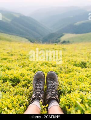 Bottes de tourisme solitaire sur la colline des montagnes couvertes de brousse de myrtille luxuriante. Photographie de paysage Banque D'Images