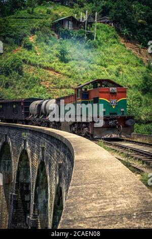 Train vert et rouge sur le célèbre pont de neuf arches dans les montagnes près d'Ella, Sri Lanka. Jungle et plantation de thé tout autour. Banque D'Images