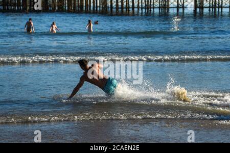 Brighton UK 6 août 2020 - ce jeune homme aime glisser dans la mer sur la plage de Brighton lors d'une belle soirée ensoleillée comme les températures devraient atteindre plus de 30 degrés dans le Sud-est de nouveau demain : crédit Simon Dack / Alay Live News Banque D'Images