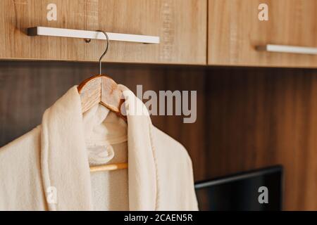 Deux peignoirs blancs à l'intérieur d'une armoire avec une porte ouverte et une niche de télévision. Banque D'Images