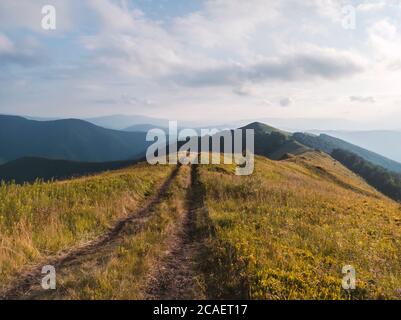 Scène incroyable sur les montagnes d'automne. Herbe orange et route rurale dans la lumière du soleil fantastique du matin. Carpates, Europe. Photographie de paysage Banque D'Images