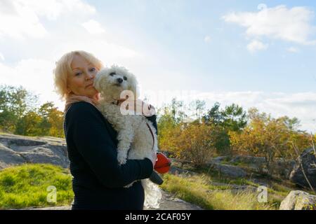 Femme âgée tenant son chien et debout sur un rocher dans les montagnes Banque D'Images