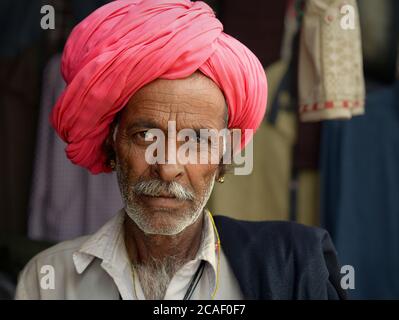 Homme indien âgé de Rajasthani avec turban rose pose pour la caméra. Banque D'Images