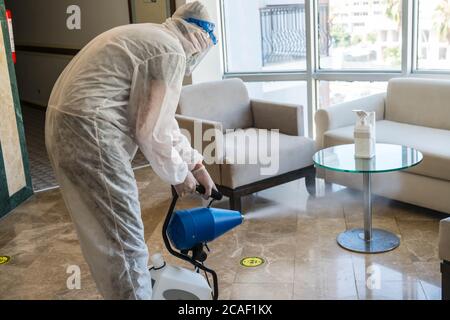 Homme en costume de protection blanc dans l'hôtel vaporise les chambres d'hôtel, ascenseur pour empêcher la contamination du virus corona.ULV machine de brouillard froid Banque D'Images