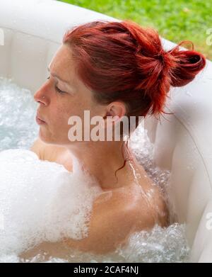 Portrait d'une femme à la tête rouge assez naturelle qui se détend dans son jacuzzi Banque D'Images