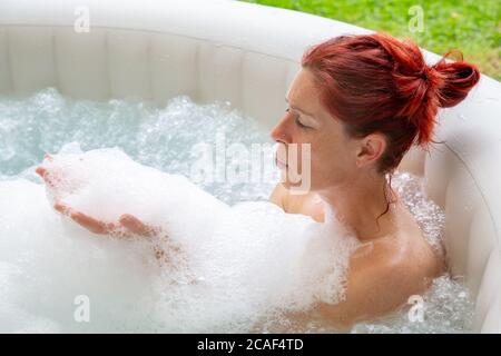 Portrait d'une femme à la tête rouge assez naturelle qui se détend dans son jacuzzi Banque D'Images