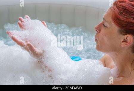 Portrait d'une femme à la tête rouge assez naturelle qui se détend dans son jacuzzi Banque D'Images