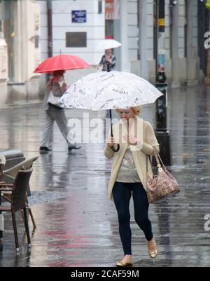 Belgrade, Serbie - 5 août 2020 : femme élégante âgée marchant sous un parapluie lors d'une journée pluvieux d'été dans la ville Banque D'Images