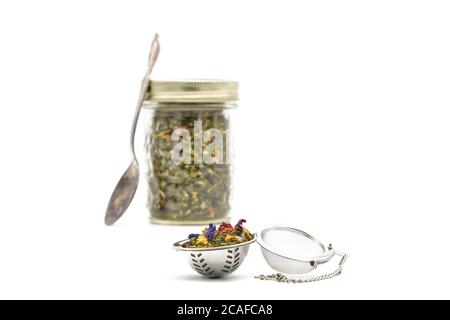 Tisane colorée dans un infuser d'argent sur un fond blanc photographié gros plan. Banque D'Images