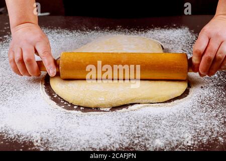 Femme roulant de pâte avec rollpin en bois pour beignets. Banque D'Images