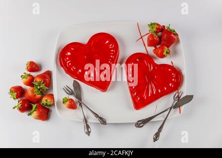 Dessert de coeur de gélatine douce dans le plat blanc avec des fraises fraîches. Concept de la Saint-Valentin. Banque D'Images