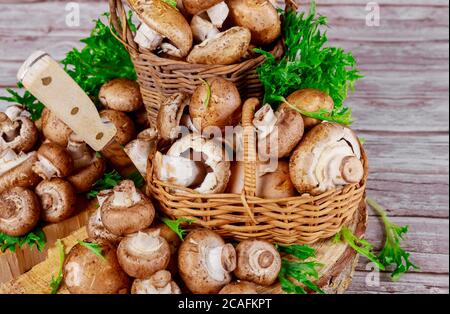 Champignons de portobello bruns dans un panier en bois d'osier avec décoration en herbe sur fond de bois. Banque D'Images