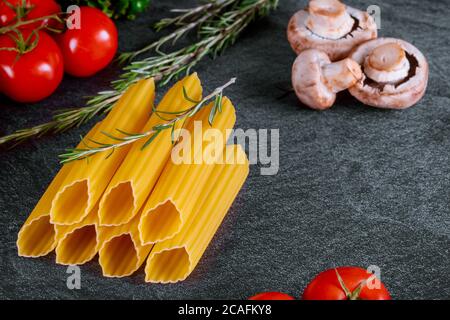 Grosses pâtes crues à la tomate, aux champignons et au romarin. Banque D'Images