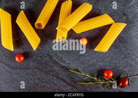 Pâtes italiennes de blé dur avec tomates fraîches et champignons sur fond sombre. Banque D'Images