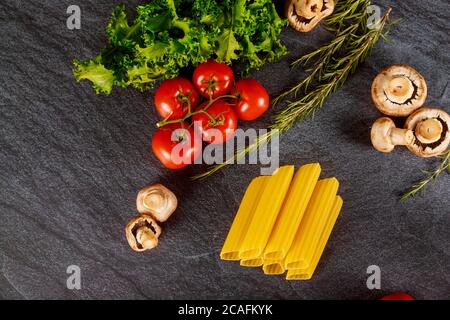 Pâtes de blé dur biologique aux tomates fraîches et aux champignons sur fond sombre. Banque D'Images