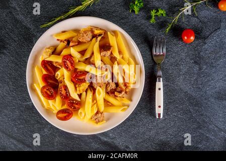 Penne pâtes avec viande et tomates cerises dans un bol blanc sur fond noir. Vue de dessus Banque D'Images