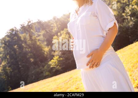 Cliché sélectif d'une femme enceinte vêtue de blanc profiter du soleil Banque D'Images