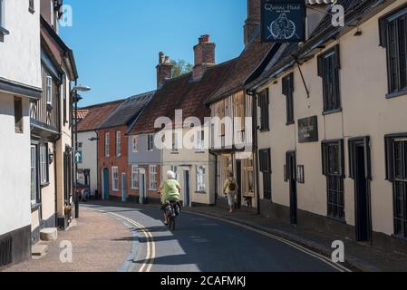 Norfolk été Royaume-Uni, vue arrière en été d'une femme senior faisant du vélo le long d'une rue typique de la ville de marché à Wymondham, Norfolk, Angleterre, Royaume-Uni Banque D'Images