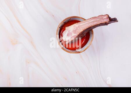 Trempez des côtes de bœuf fumées dans une sauce Chili chaude Banque D'Images