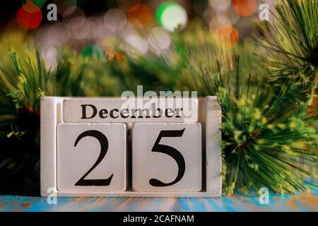 Le 25 décembre sur cube de calendrier en bois avec arrière-plan de lumières d'arbre de noël. Concept de Noël Banque D'Images