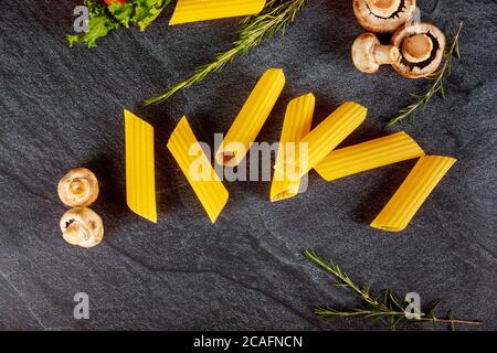 Pâtes manucotti non cuites aux champignons et au romarin sur fond noir. Banque D'Images
