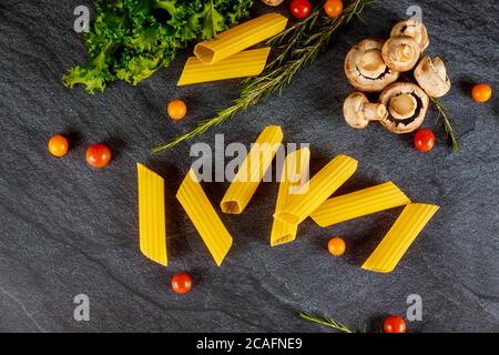 Pâtes biologiques manucotti aux champignons et aux tomates sur fond noir. Banque D'Images