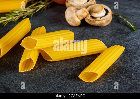 Pâtes sèches cannelloni aux champignons et aux tomates sur fond noir. Cuisine italienne. Banque D'Images