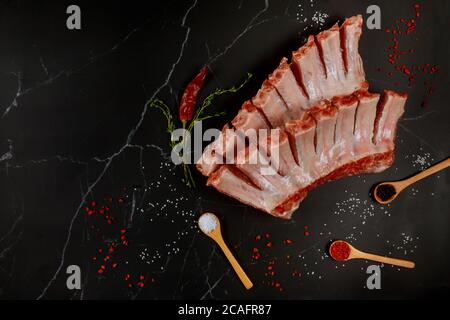 Côtelettes de bœuf de filet crues avec assaisonnement sur fond noir. Banque D'Images