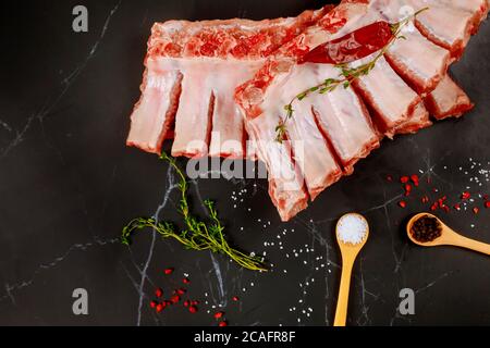 Côtes de porc de porc de filet crues avec assaisonnement sur fond noir. Banque D'Images