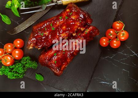 Côtes de bœuf avec sauce barbecue sur panneau en pierre noire. Vue de dessus. Banque D'Images