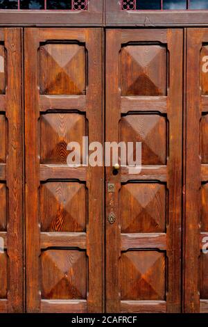 Portes en bois marron avec carrés convexes sous une grille métallique à l'entrée. Banque D'Images