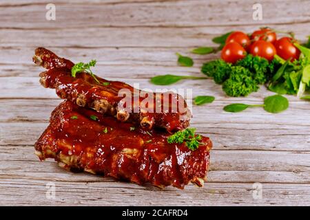 Côtelettes de bœuf juteux cuites au barbecue avec tomates et épinards sur bois. Banque D'Images
