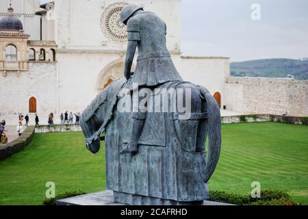 Assise, italie - juin 30 2020 : célèbre sculpture en bronze devant l'église saint françois d'Assise avec des pèlerins en visite en italie Banque D'Images