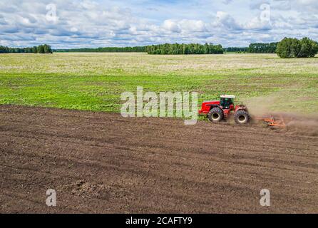 une grande machine agricole cultive la terre. La vue du dessus. Labourage de terres pour planter des cultures. Photos de la vue de l'oiseau avec Banque D'Images