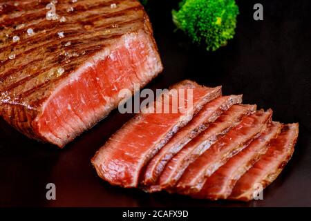 Bifteck de bœuf angus rare en tranches grillées sur un tableau noir. Gros plan. Banque D'Images