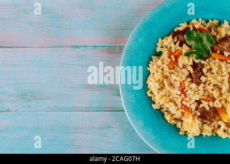 Riz frit avec légumes et poulet sur plaque et fond bleu. Cuisine chinoise. Banque D'Images