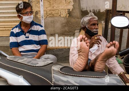 jaisalmer, rajasthan / inde - juillet 22 2020 : deux hommes d'âge moyen se détendant assis des jambes sur le véhicule regardant sur leur gauche Banque D'Images