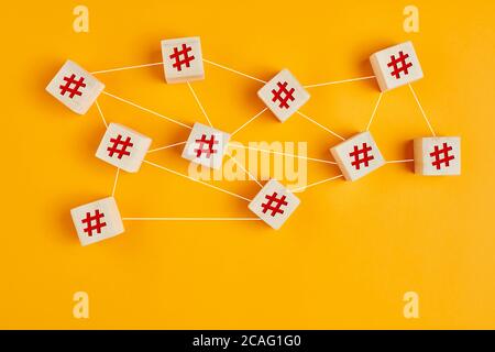 Symboles hashtag sur des cubes en bois reliés les uns aux autres avec des lignes sur fond jaune. Connexion hashtag, recherche ou thème de tendance sur les réseaux sociaux Banque D'Images