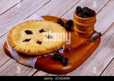Tarte ronde à la mûre sur une table en bois avec une cuillère et des baies fraîches. Banque D'Images