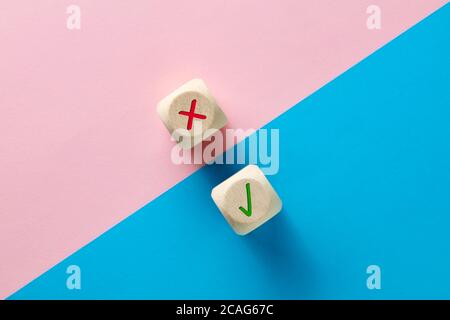 Symboles faux et droit sur des cubes en bois sur fond rose et bleu. Examen ou test évaluation, approbation ou désapprobation, vote oui ou non, positif ou n Banque D'Images