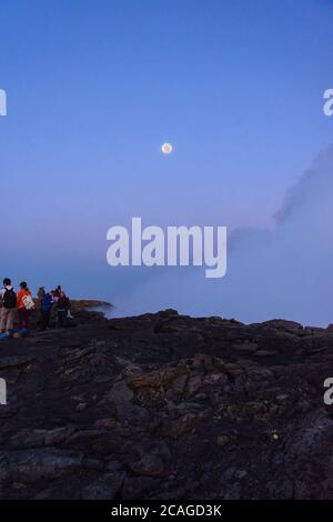 Silhouettes de personnes assises au bord du cratère du volcan Erta Ale, en Éthiopie, en pleine lune Banque D'Images