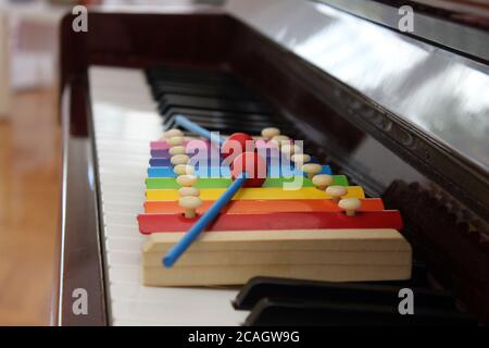 Gros plan d'un jouet xylophone coloré avec des maillets mis sur le clavier d'un piano classique. Banque D'Images