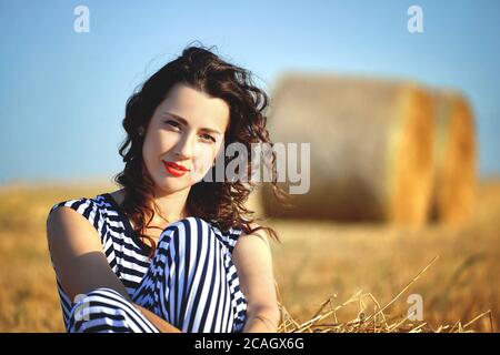 belle fille dans une robe rayée posant dans l'été dans le champ Banque D'Images