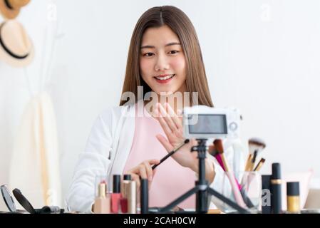 Belle beauté asiatique vlogger influenceur en direct de diffusion en face de appareil photo à la maison Banque D'Images