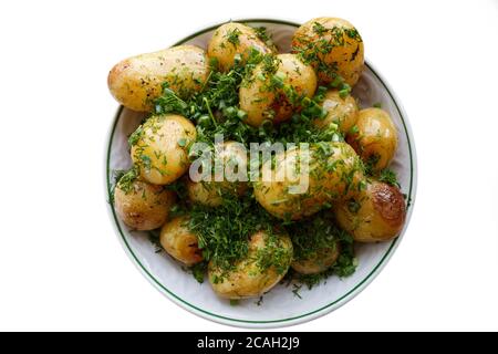 Jeunes pommes de terre frites rondes dans une assiette de kirami parsemée d'aneth finement haché. Isolé sur fond blanc. Banque D'Images